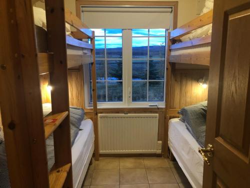 レイクホルトにあるEyjasol Cottagesの二段ベッド2台と窓が備わる客室です。