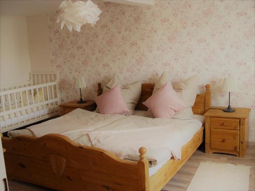 a bedroom with a wooden bed with pink pillows at Ferienhaus Kaline in Grebenhain