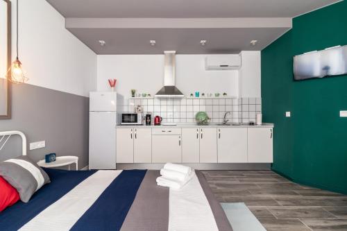 una cocina con armarios blancos y una pared verde en Apartamentos Navío en Valencia