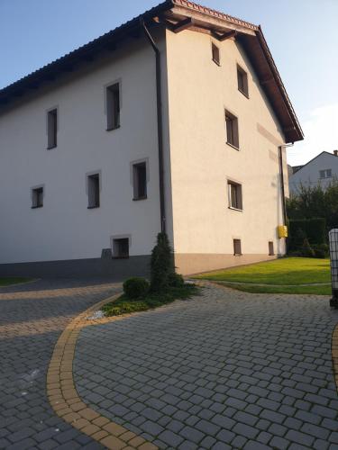 um grande edifício branco numa estrada de tijolos em ,,Dom na Wzgórzach,, em Bachowice