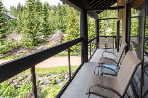 a screened porch with chairs and a view of the woods at The Ironwood on Blueberry Hill in Whistler