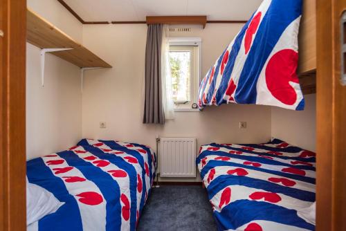 1 dormitorio con 2 camas y bandera en Groot hoek Chalet met Airco ,Wasmachine, Vaatwasser,Droger en luxe keuken en zwembad op camping! Immer Besser!, en Rijs