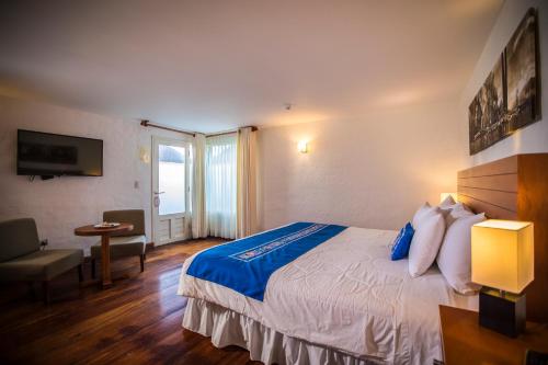 a hotel room with a large bed and a table at Aranwa Pueblito Encantado del Colca in Coporaque