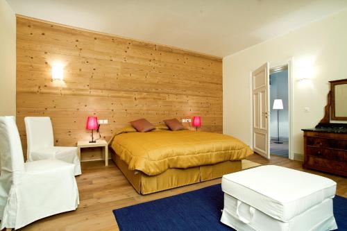 a bedroom with a bed and a wooden wall at Maloja Palace Suites CO2-Neutral in Maloja