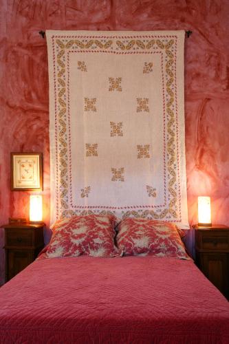 a bed with a red comforter and two lamps at Casa Rural Los Pedregales in Carenas