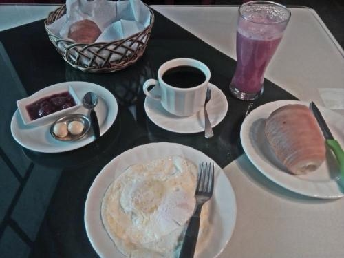 a table with plates of breakfast food and a cup of coffee at El Pedron Hotel in Baños