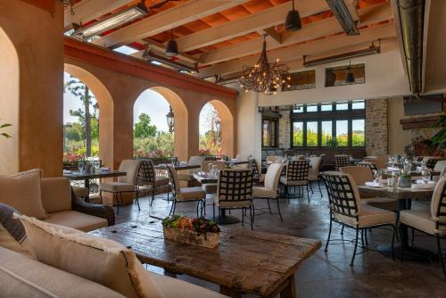 un restaurante con mesas, sillas y ventanas en Westlake Village Inn, en Westlake Village