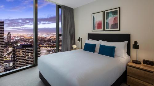 a bedroom with a large white bed and large windows at Avani Melbourne Central Residences in Melbourne