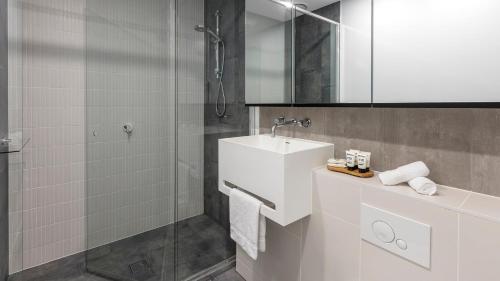 a white bathroom with a sink and a shower at Avani Melbourne Central Residences in Melbourne