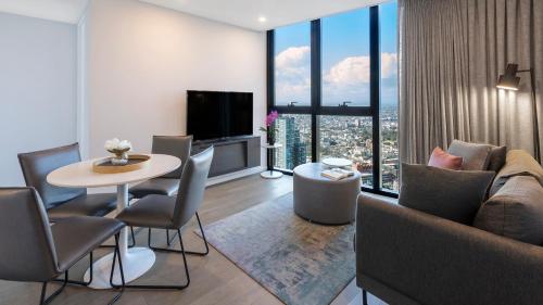a living room with a couch and a table with chairs at Avani Melbourne Central Residences in Melbourne