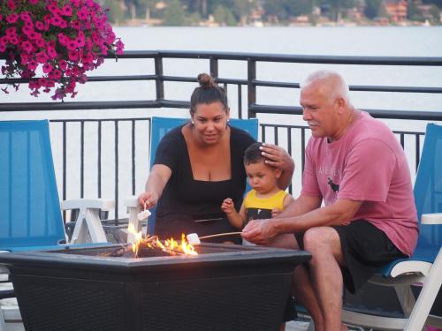 a man and a woman and a child sitting next to a fire pit at The Lake Motel in Lake George