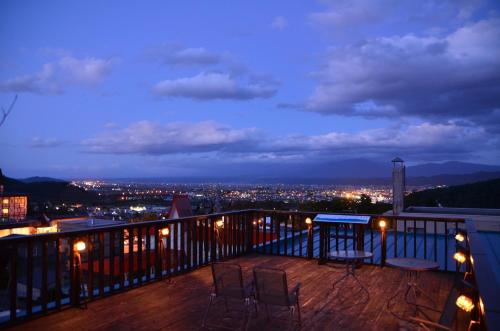 a balcony with two chairs and a city at night at Hotel Naturwald Furano in Furano
