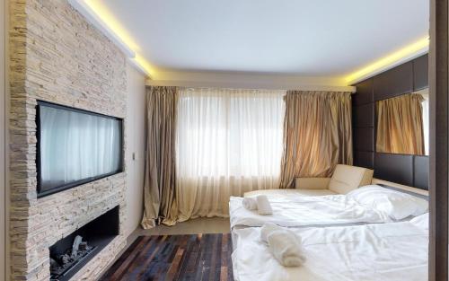 1 Schlafzimmer mit 2 Betten, einem TV und einer Ziegelwand in der Unterkunft Suot Brattas in St. Moritz