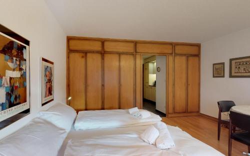 Schlafzimmer mit einem großen weißen Bett mit einem Kopfteil aus Holz in der Unterkunft Suot Brattas 21 in St. Moritz
