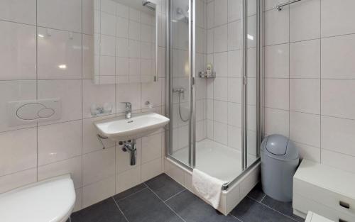 uma casa de banho com um chuveiro, um lavatório e um WC. em Suot Brattas 21 em St. Moritz