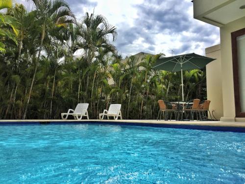 a swimming pool with a table and chairs and an umbrella at Lagos del Peñon: Casa 10 - Puerto Madero in Girardot