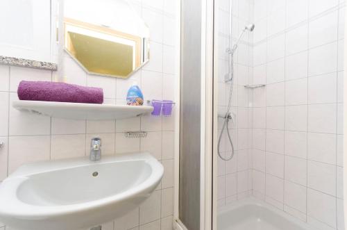 a white bathroom with a sink and a shower at Apartment and Room Ilija in Tribunj