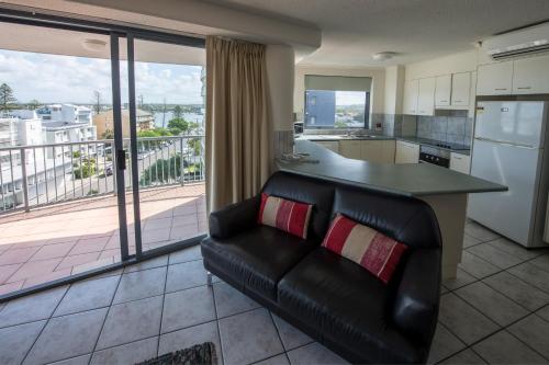 a living room with a couch and a kitchen with a counter at Centrepoint Apartments Caloundra in Caloundra