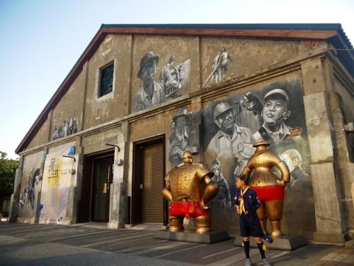 a building with a mural on the side of it with two statues at Wenpin Hotel - Pier 2 in Kaohsiung