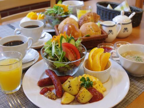 a table with a plate of breakfast foods and drinks at Hakuba Goryu Pension Kurumi in Hakuba
