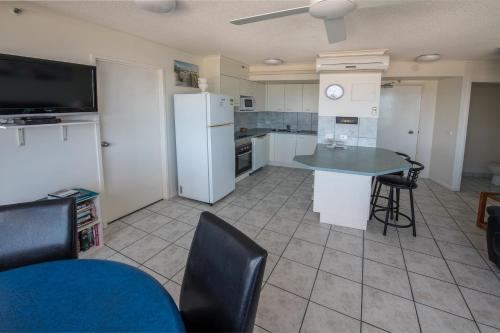 a kitchen with a refrigerator and a table and chairs at Centrepoint Apartments Caloundra in Caloundra
