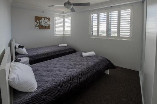 a bedroom with two beds and two windows at Centrepoint Apartments Caloundra in Caloundra