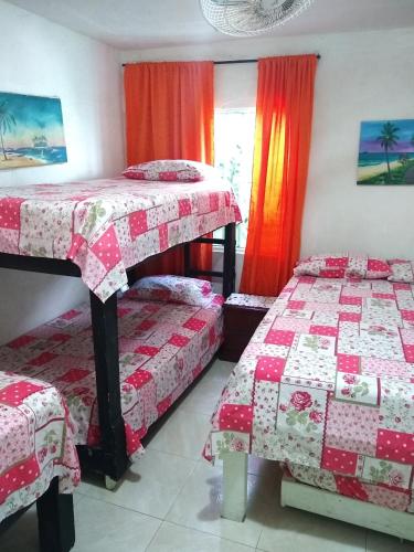 two beds in a room with red curtains at Posada Green Sea San Luis pesos with breakfast included starting in March in Cueva de Morgan