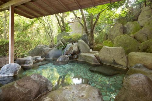 a pool of water with rocks in a garden at Hakuunsou in Yugawara