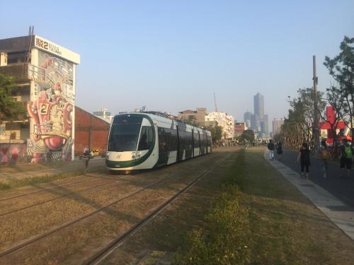 a train traveling down the tracks in a city at Wenpin Hotel - Pier 2 in Kaohsiung