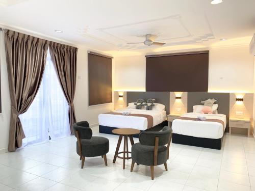 a hotel room with two beds and a table and chairs at Langkawi Cozy Holiday Home at Taman Seri Aman by Zervin in Kuah