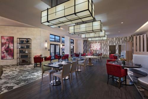 a dining room with tables and red chairs at Hyatt Centric The Woodlands in The Woodlands