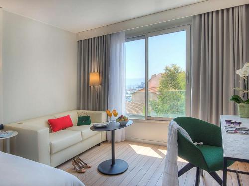 a hotel room with a couch and a table and a window at Mercure Ajaccio in Ajaccio