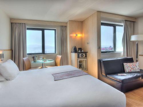a hotel room with a large bed and a chair at Mercure Ajaccio in Ajaccio