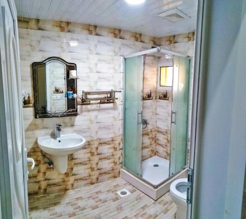 a bathroom with a shower and a sink and a toilet at Almudawah Hotel in Ţurayf