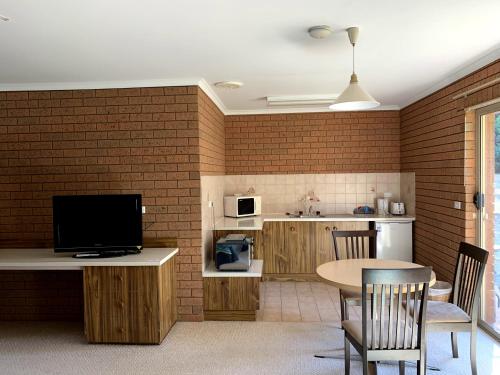 a kitchen with a table and a tv in a room at Kingswood Motel in Tocumwal