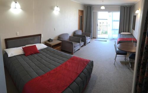 a hotel room with a bed and a living room at Amber Court Motel in New Plymouth