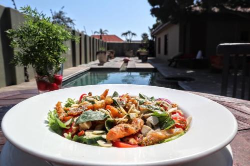 a white bowl filled with pasta and vegetables at Singa Lodge - Lion Roars Hotels & Lodges in Port Elizabeth