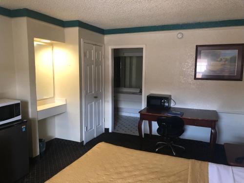 a hotel room with a desk and a bed at Americas Best Value Inn Denver in Denver