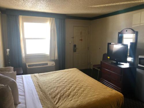 a bedroom with a bed and a television and a window at Americas Best Value Inn Denver in Denver