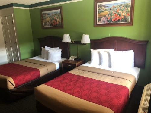 two beds in a hotel room with green walls at Americas Best Value Inn Denver in Denver