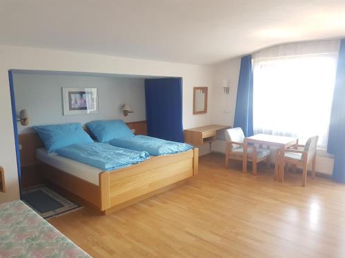een slaapkamer met een bed met blauwe lakens en een tafel bij Rooftop Apartment in Bad Hofgastein