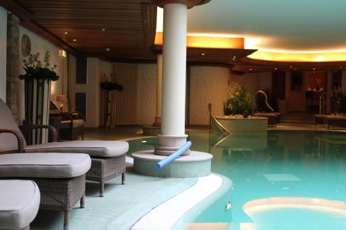 a pool in a hotel with chairs and a pillar at Hotel Landhaus Wachtelhof in Rotenburg an der Wümme
