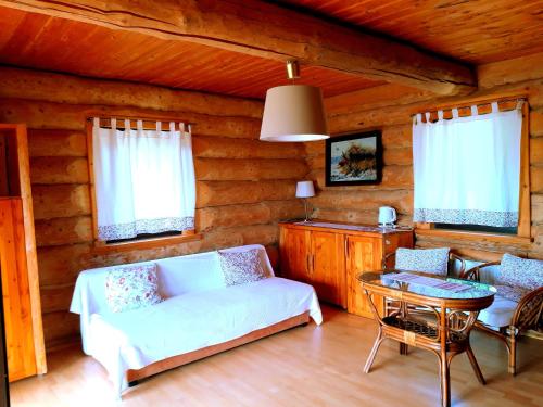 ein Wohnzimmer mit einem Sofa und einem Tisch in der Unterkunft Wilcza Jama - domki z bali in Lutowiska