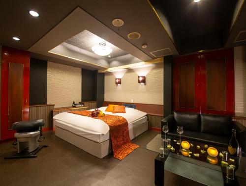 a bedroom with a bed and a couch and a chair at Hotel Gee (Adult Only) in Sakai