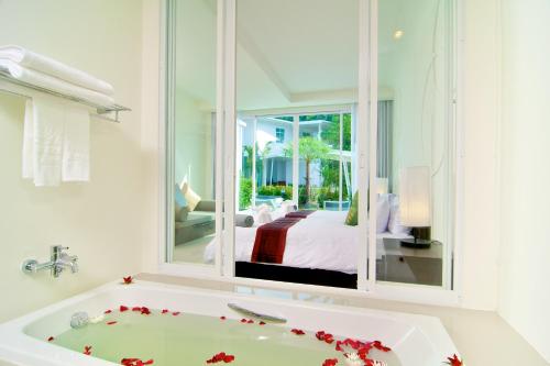 uma casa de banho com uma banheira e uma cama numa janela em The Palmery Resort em Kata Beach