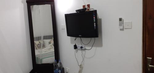 a television hanging on a wall next to a mirror at Nature Night Homestay in Sigiriya