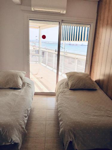 two beds in a room with a view of the beach at Pineda Beach PORT AVENTURA in La Pineda