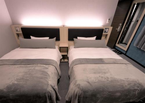 two beds sitting next to each other in a room at Green Rich Hotel Tottori Ekimae (Artificial hot spring Futamata Yunohana) in Tottori