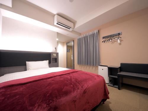 a bedroom with a red bed and a chair at Green Rich Hotel Tottori Ekimae (Artificial hot spring Futamata Yunohana) in Tottori