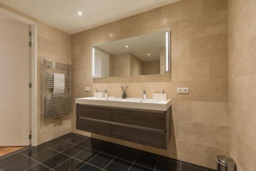 une salle de bain avec un lavabo et un miroir dans l'établissement Lage Wurft Beach Apartments, à Noordwijk